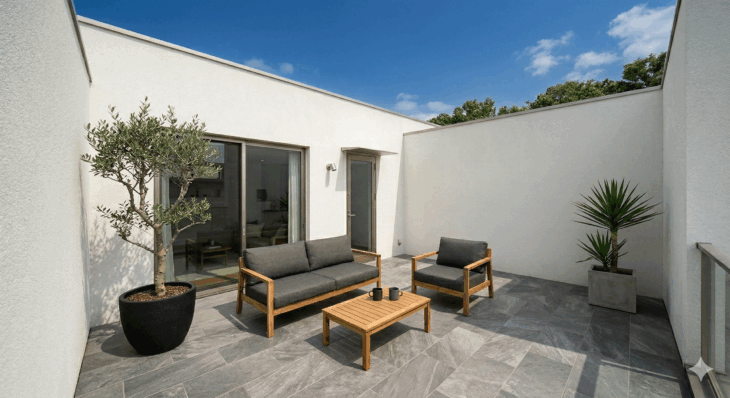 タイル床のテラス。四方を壁で囲われた空間にソファセットが置かれたいる。